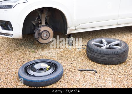 Changing a tyre (tire) on a car, changing a wheel with car on a jack. Part of a series of photos depicting changing a flat tyre Stock Photo