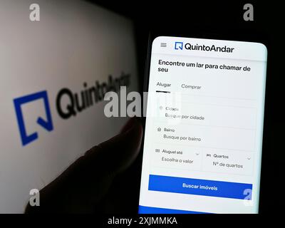 Stuttgart, Germany, 09-10-2022: Person holding cellphone with webpage of company QuintoAndar Servicos Imobiliarios Ltda. on screen with logo. Focus Stock Photo