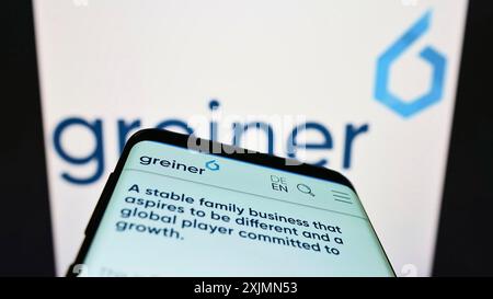 Stuttgart, Germany, 09-11-2022: Mobile phone with website of Austrian plastics company Greiner AG on screen in front of business logo. Focus on Stock Photo