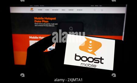 Stuttgart, Germany, 10-17-2022: Person holding mobile phone with logo of American telecommunications company Boost Mobile on screen in front of web Stock Photo