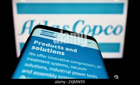 Stuttgart, Germany, 10-23-2022: Mobile phone with webpage of Swedish industrial company Atlas Copco AB on screen in front of business logo. Focus on Stock Photo