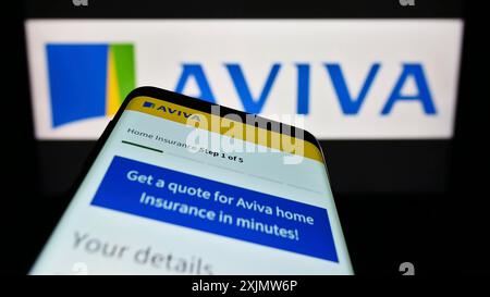 Stuttgart, Germany, 11-30-2022: Mobile phone with webpage of British insurance company Aviva plc on screen in front of business logo. Focus on Stock Photo