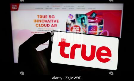 Stuttgart, Germany, 10-23-2022: Person holding cellphone with logo of Thai telecommunications company True Corporation on screen in front of webpage. Stock Photo