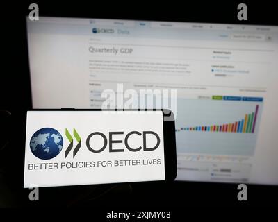 Stuttgart, Germany, 12-23-2022: Person holding smartphone with logo of intergovernmental organisation OECD on screen in front of website. Focus on Stock Photo