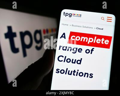 Stuttgart, Germany, 12-30-2022: Person holding cellphone with webpage of Australian company TPG Telecom Limited on screen in front of logo. Focus on Stock Photo