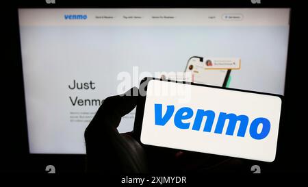 Stuttgart, Germany, 12-31-2022: Person holding smartphone with logo of mobile payment service Venmo on screen in front of website. Focus on phone Stock Photo