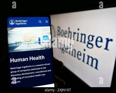 Stuttgart, Germany, 01-11-2023: Person holding smartphone with webpage of pharmaceutical company Boehringer Ingelheim on screen with logo. Focus on Stock Photo