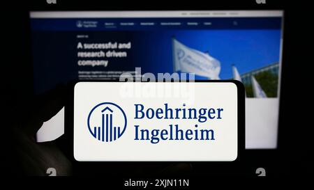 Stuttgart, Germany, 01-11-2023: Person holding smartphone with logo of pharmaceutical company Boehringer Ingelheim on screen in front of website. Stock Photo