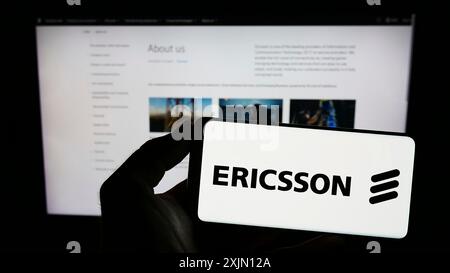 Stuttgart, Germany, 01-11-2023: Person holding smartphone with logo of Swedish telecommunications company Ericsson on screen in front of website. Stock Photo