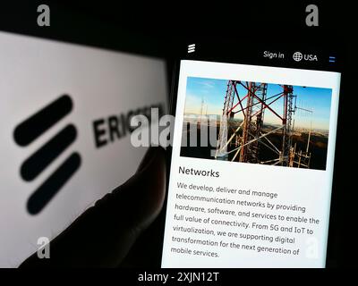 Stuttgart, Germany, 01-11-2023: Person holding cellphone with webpage of Swedish telecommunications company Ericsson on screen in front of logo. Stock Photo