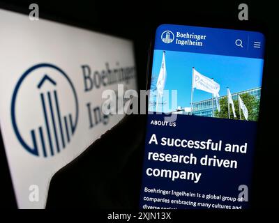 Stuttgart, Germany, 01-11-2023: Person holding mobile phone with website of pharmaceutical company Boehringer Ingelheim on screen with logo. Focus on Stock Photo