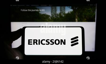 Stuttgart, Germany, 01-11-2023: Person holding cellphone with logo of Swedish telecommunications company Ericsson on screen in front of business Stock Photo