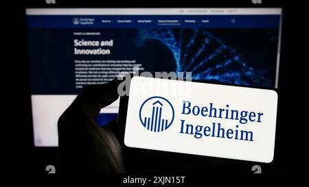 Stuttgart, Germany, 01-11-2023: Person holding cellphone with logo of pharmaceutical company Boehringer Ingelheim on screen in front of business Stock Photo