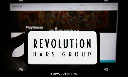 Stuttgart, Germany, 01-25-2023: Person holding cellphone with logo of hospitality company Revolution Bars Group plc on screen in front of webpage. Stock Photo