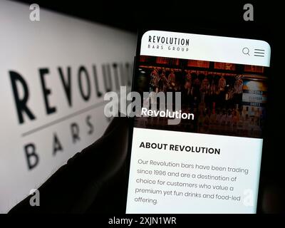 Stuttgart, Germany, 01-25-2023: Person holding cellphone with webpage of hospitality company Revolution Bars Group plc on screen with logo. Focus on Stock Photo