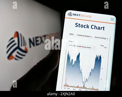 Stuttgart, Germany, 03-07-2023: Person holding smartphone with webpage of US energy company NextDecade Corporation on screen in front of logo. Focus Stock Photo