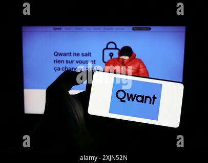 Stuttgart, Germany, 04-23-2023: Person holding mobile phone with logo of French search engine company Qwant SAS on screen in front of business web Stock Photo