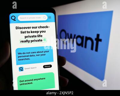 Stuttgart, Germany, 04-23-2023: Person holding cellphone with web page of French search engine company Qwant SAS on screen in front of logo. Focus on Stock Photo