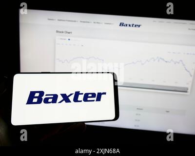 Stuttgart, Germany, 03-31-2023: Person holding cellphone with logo of American healthcare company Baxter International Inc. on screen in front of Stock Photo