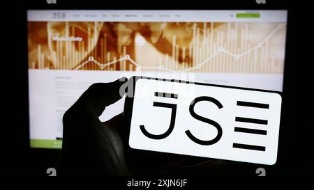 Stuttgart, Germany, 03-25-2023: Person holding cellphone with logo of JSE Limited (Johannesburg Stock Exchange) on screen in front of business Stock Photo