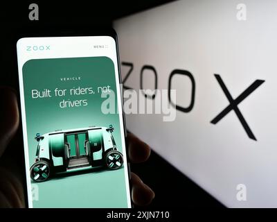 Stuttgart, Germany, 03-19-2023: Person holding smartphone with web page of US autonomous vehicle company Zoox Inc. on screen in front of logo. Focus Stock Photo