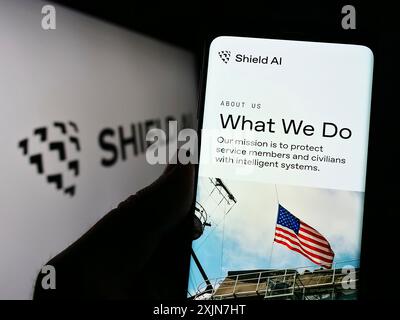 Stuttgart, Germany, 06-18-2023: Person holding cellphone with webpage of US aerospace and defense company Shield AI on screen in front of logo. Focus Stock Photo