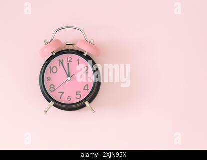 Pastel pink and black alarm clock on light pastel pink background with copy space. Minimal time concept. Flat lay. Stock Photo