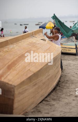 Lima - Peru, May 21, 2023 - In Lima's fishing port, the morning is dedicated to repairing nets and preparing boats. Fishermen skillfully mend their ne Stock Photo