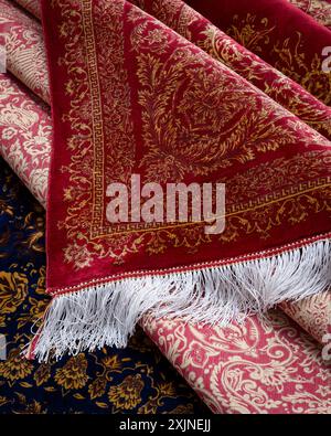 Exquisite red Persian carpet with intricate golden patterns and white fringe detail. Stock Photo