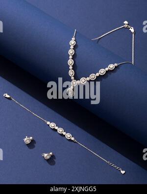Exquisite diamond jewelry set on a dark blue background, including necklace, bracelet, and earrings. Stock Photo
