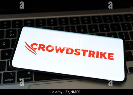 CrowdStrike logo seen on screen of smartphone plased on laptop. Cybersecurity company behind the global IT outage. Stafford, United Kingdom, July 19, Stock Photo