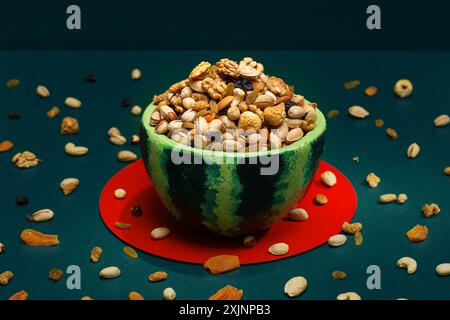 A decorative bowl filled with a variety of nuts on a green background. For Yalda nights Stock Photo