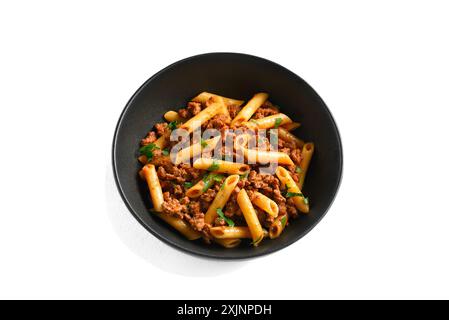 Penne pasta with minced meat, tomato sauce and greens in black ceramic bowl isolated on white background. Bowl of pasta bolognese Stock Photo