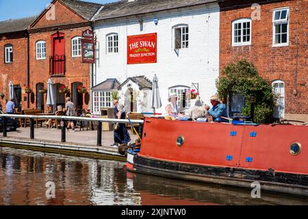 Canal narrowboat moored outside the Swan inn public house on the Trent and Mersey canal at Fradley Junction between Alrewas and Fradley Staffordshire Stock Photo