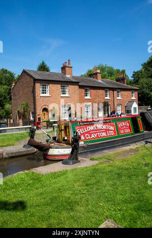 Former Fellows Morton and Clayton working canal narrowboat Perch, passing through the locks  and canalside cottages at Fradley Junction Staffordshire Stock Photo