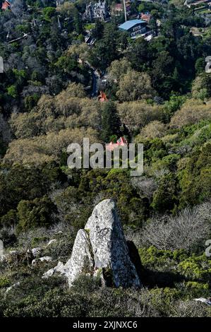 Elevated view of lush green forest with a rocky peak and historic buildings at the moorish castle in Sintra Stock Photo