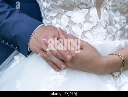 hands with wedding rings. hands of the bride and groom with wedding rings on the background of a white dress. the groom gently holds the bride's hand. Stock Photo