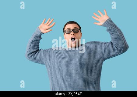 Scared young man in 3D glasses on blue background Stock Photo