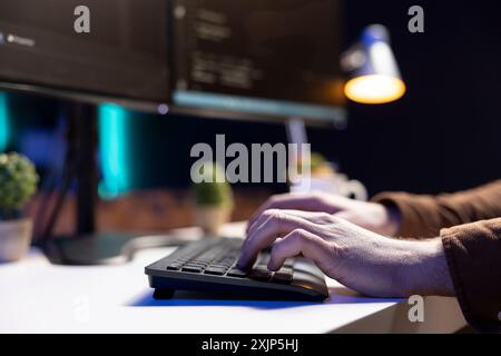 Programmer typing on keyboard, implementing and maintaining security measures to protect company systems and data. Expert writing, testing and debugging Java code for software applications, close up Stock Photo