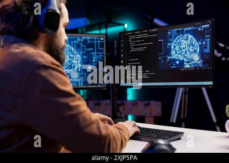 Programmer listening music while doing maintenance on artificial intelligence neural networks computerized model. Tech support expert using headphones and doing checkup on AI systems Stock Photo