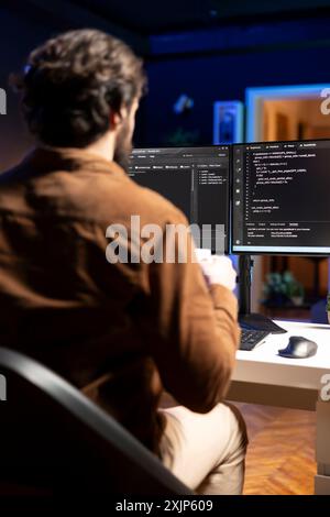Computer engineer doing software quality assurance, reading source code on screen before implementing it. IT admin inspecting coding on desktop PC, looking to fix potential issues Stock Photo