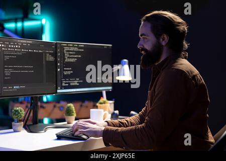 Freelancing computer engineer typing on keyboard, implementing security measures to protect company systems and data. Remote IT worker testing and debugging code for software applications Stock Photo