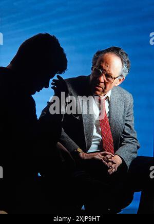 Therapist counseling very troubled and depressed young man. The patient is in silhouette and unidentified Stock Photo