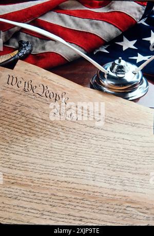 A close-up image of the United States Constitution document, open to the first page with the beginning lines We The People, lies flat on a dark wooden Stock Photo