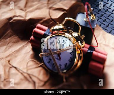 A gold alarm clock is attached to a stick of dynamite with a length of twine. To make a time bomb. Stock Photo