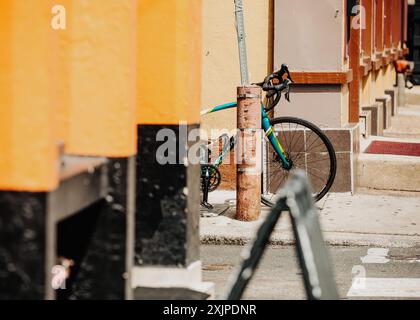 A colorful bicycle is locked to a pole on a city street, partially obscured by a black and yellow structure in Philly Stock Photo