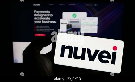 Stuttgart, Germany, 07-08-2023: Person holding cellphone with logo of payments company Nuvei Technologies Corp. on screen in front of business Stock Photo