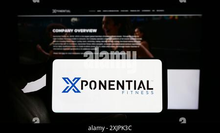 Stuttgart, Germany, 07-08-2023: Person holding cellphone with logo of American franchise company Xponential Fitness Inc. on screen in front of Stock Photo