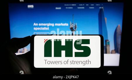 Stuttgart, Germany, 07-08-2023: Person holding cellphone with logo of telecommunications company IHS Holding Limited on screen in front of webpage. Stock Photo