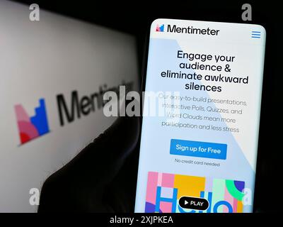 Stuttgart, Germany, 07-09-2023: Person holding smartphone with webpage of presentation software company Mentimeter on screen in front of logo. Focus Stock Photo